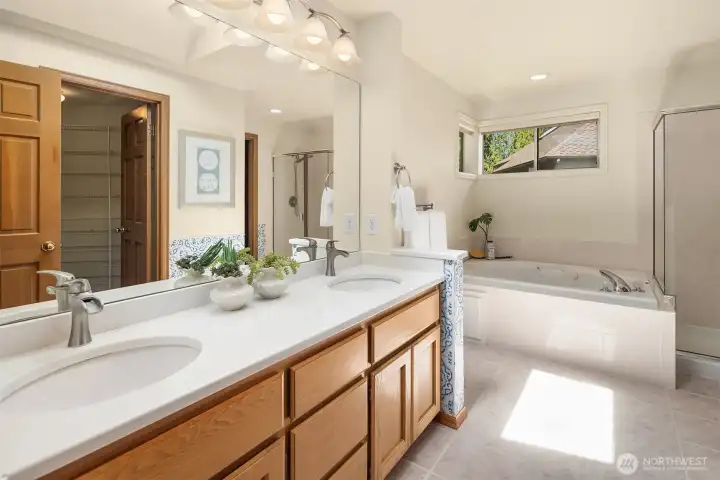 Dual sinks w/ Quartz Counters in the master bathroom, corner jetted tub, separate shower, toilet room, a walk-in closet, and skylight