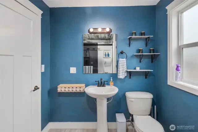 A full look at the bathroom, shelves, mirror, sink, toilet.