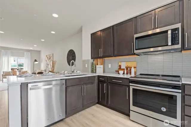 Contemporary kitchen with stainless steel appliances, quartz countertops, and full-height tile backsplash.