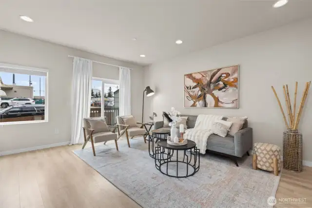 Bright and open living room with oversized windows, luxury vinyl plank flooring, and mini-split heating and A/C.