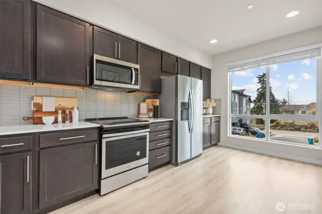 Contemporary kitchen with stainless steel appliances, quartz countertops, and full-height tile backsplash.