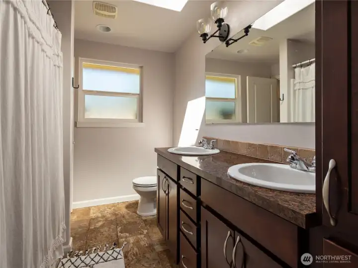Primary bathroom with skylight, lots of cabinets & a closet for bath towels etc.,,