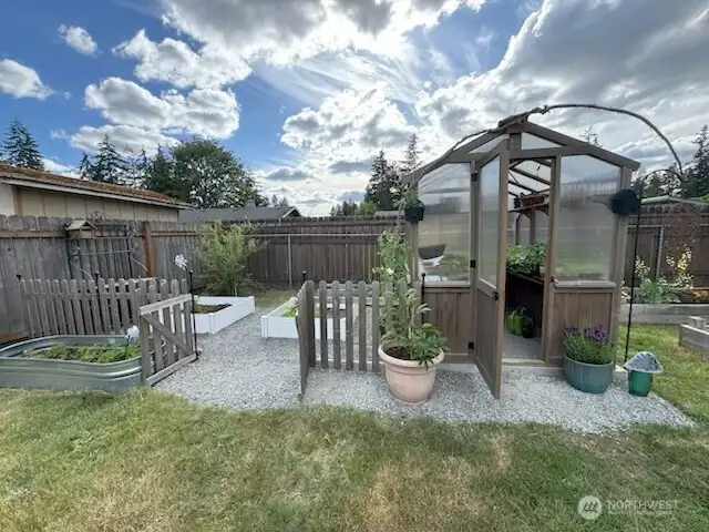 Beautiful Greenhouse & garden area ready for your planting. Pink lemonade blueberry bush in the back left corner.