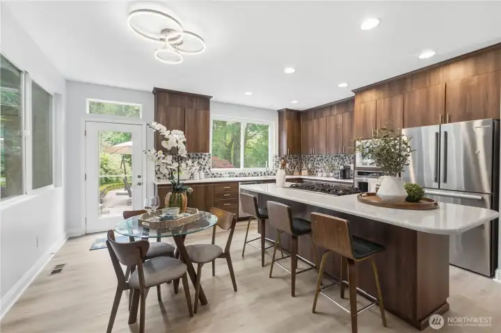 A bright perspective of the spacious kitchen showcasing the large island and an eating area that easily accommodates a much larger table. A bright perspective of the spacious kitchen showcasing the large island and an eating area that easily accommodates a much larger table.