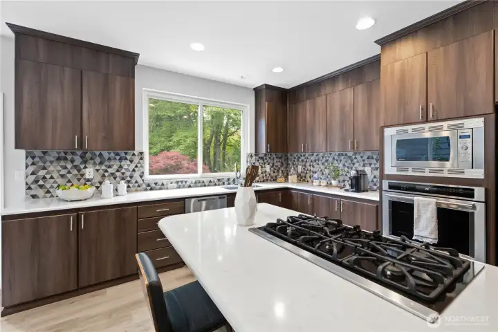 A spacious island with gas cooktop anchors the remodeled kitchen, complemented by gorgeous tile details and serene backyard views. A spacious island with gas cooktop anchors the remodeled kitchen, complemented by gorgeous tile details and serene backyard views.