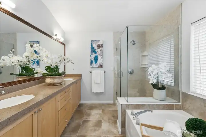 A bright, remodeled primary full bath with double sinks, featuring a separate frameless shower and a separate soaking tub for a spa-like experience. A bright, remodeled primary full bath with double sinks, featuring a separate frameless shower and a separate soaking tub for a spa-like experience.