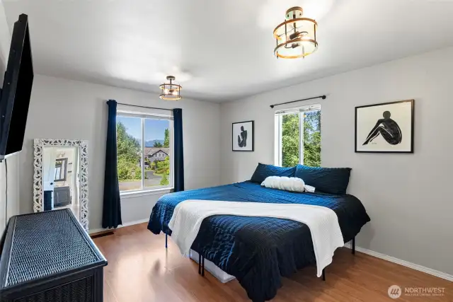 Primary bedroom with hardwood laminate flooring and plenty of light from windows.