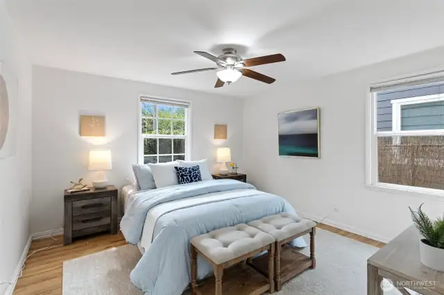 Main floor primary bedroom with hardwood oak flooring and windows facing east and south, fresh paint.