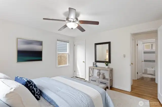 Main floor primary bedroom with hardwood oak flooring and windows facing east and south, fresh paint.