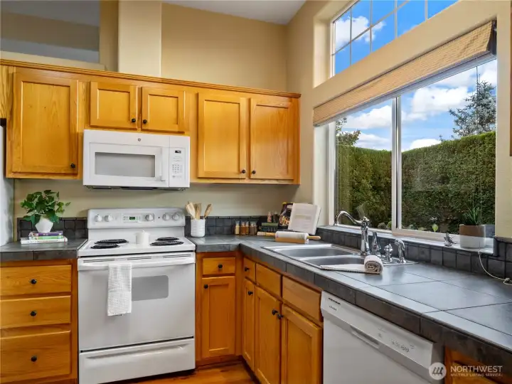 Warm wood cabinets and tasteful tile countertops...and so much light.