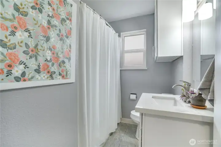 Main floor full bath with tile flooring and quartz countertops
