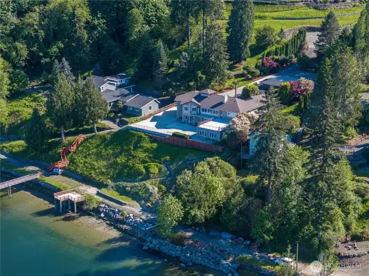 Enter this 1.19 acre waterfront retreat from the cul-de-sac just above the row of evergreens that line the left side of the private driveway.