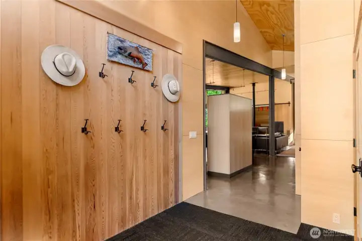 A wall of hooks adorn the beautiful cedar paneling in the home's entry. A wall of hooks adorn the beautiful cedar paneling in the home's entry.