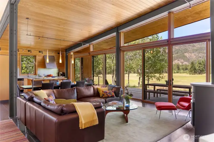Steel beams, floor-to-ceiling window walls, cedar paneling, and heated concrete floors characterize the home's interior living spaces. Steel beams, floor-to-ceiling window walls, cedar paneling, and heated concrete floors characterize the home's interior living spaces.
