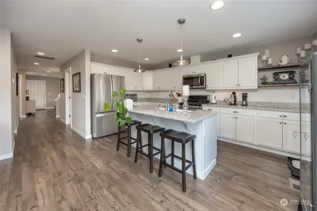 Sunny remodeled kitchen with counter space/cabinet galore, quartz countertops, stainless steel appliance and island with breakfast bar seating.
