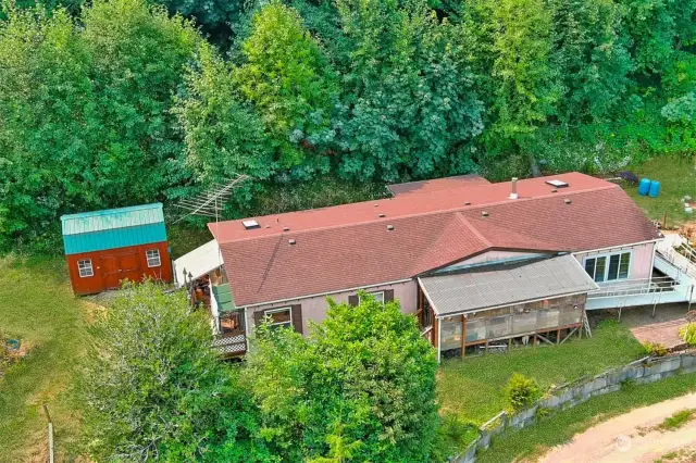 Aerial view of home and shed behind, lots of trees outline this property for additional privacy.