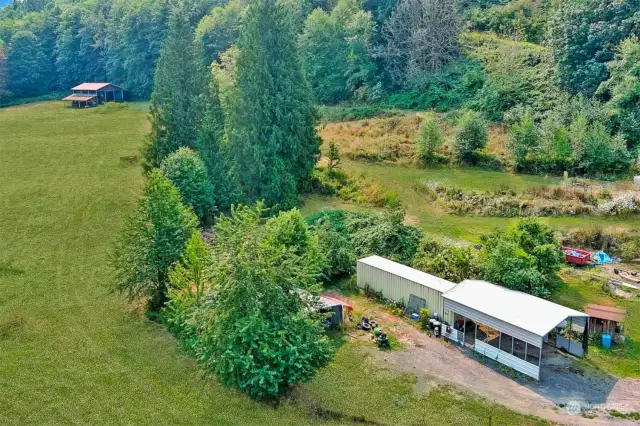 View of RV cover and conex storage with barn in the distance