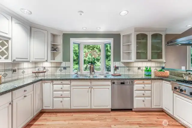 Kitchen with custom cabinets, granite counters, tiled backsplash and oak hardwood floors