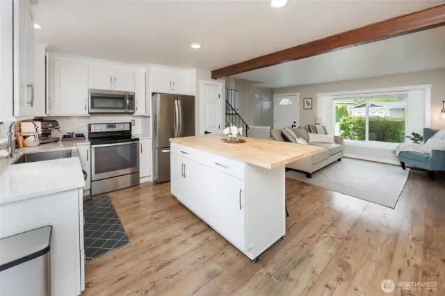 Bright open remodeled kitchen with newer cabinets, vinyl plank floors, island, quartz counters & appliances.
