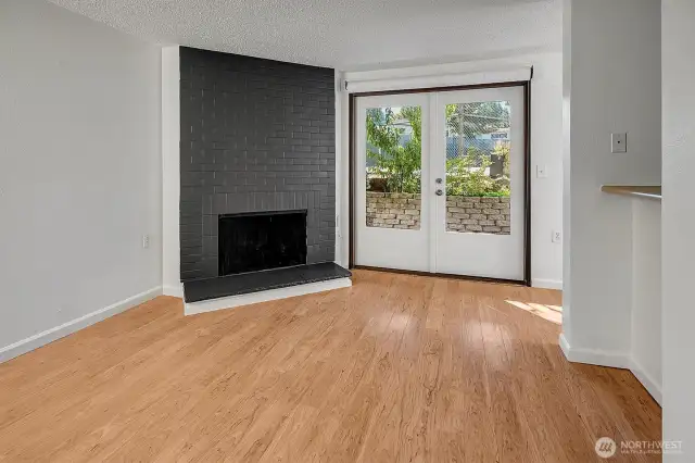 Living room with feature wood burning fireplace and French doors leading to lovely patio.