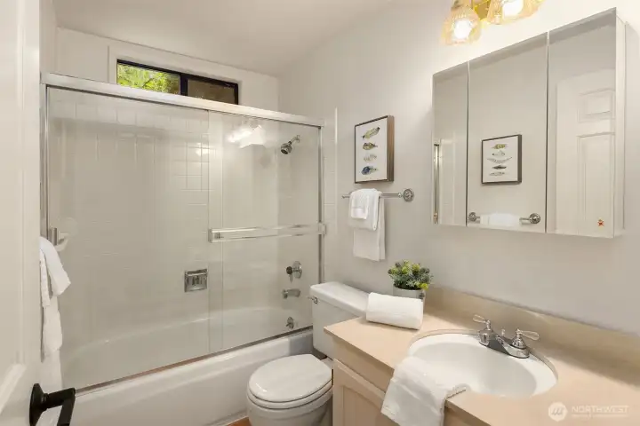 The full hall bath features newly refinished hardwood floors and a mirrored medicine cabinet.