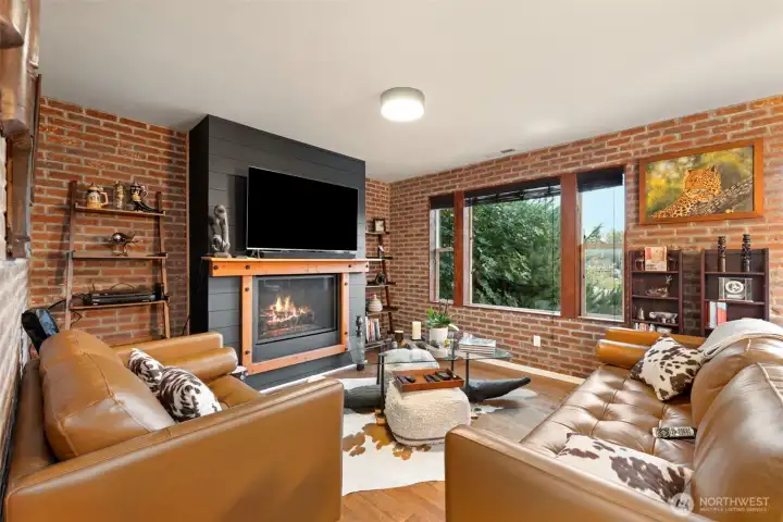 Gather and unwind in this inviting living room, where a propane-fueled fireplace creates a warm, welcoming centerpiece for cool Northwest evenings. Custom brick veneer walls add rich character and timeless charm, while oversized windows frame serene views of the lake and surrounding landscape. Whether you’re curling up for a quiet night in or entertaining guests, this space offers the perfect blend of comfort, style, and connection to the outdoors.