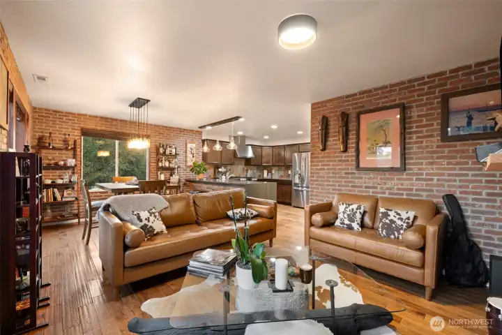 The heart of the home, this inviting great room is designed for both connection and comfort. An open flow between living, dining, and kitchen spaces creates an ideal setting for intimate entertaining — from relaxed evenings with friends to lively holiday gatherings. Warm brick veneer walls and rich wood floors add timeless character, while thoughtful lighting and a seamless layout make every corner feel both cozy and refined.