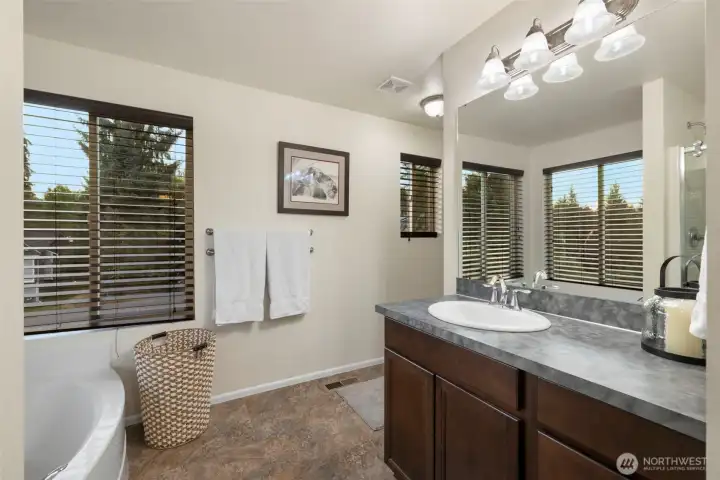 The en suite bath is designed for everyday comfort and relaxation, featuring a deep soaking tub perfect for unwinding and a separate shower for daily convenience. A spacious storage closet keeps essentials neatly tucked away, while generous windows invite in natural light. Durable vinyl flooring offers easy care without compromising on style.