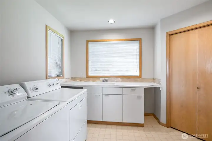 Huge utility room with big storage closet, counters, cupboards, and sink.
