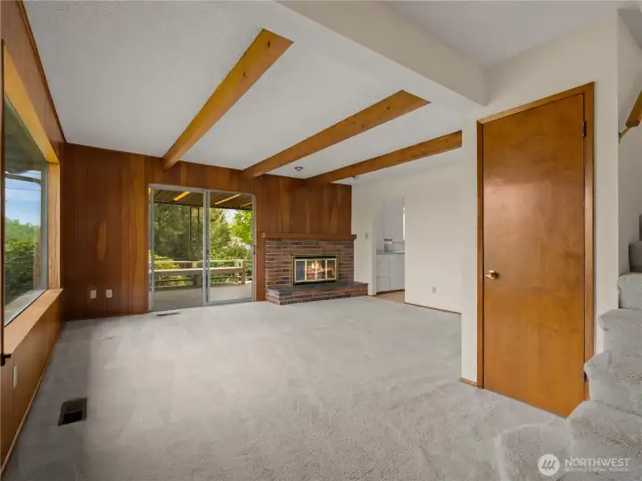 Step inside to a light-filled living room where large windows and a classic brick fireplace create a warm, inviting first impression.
