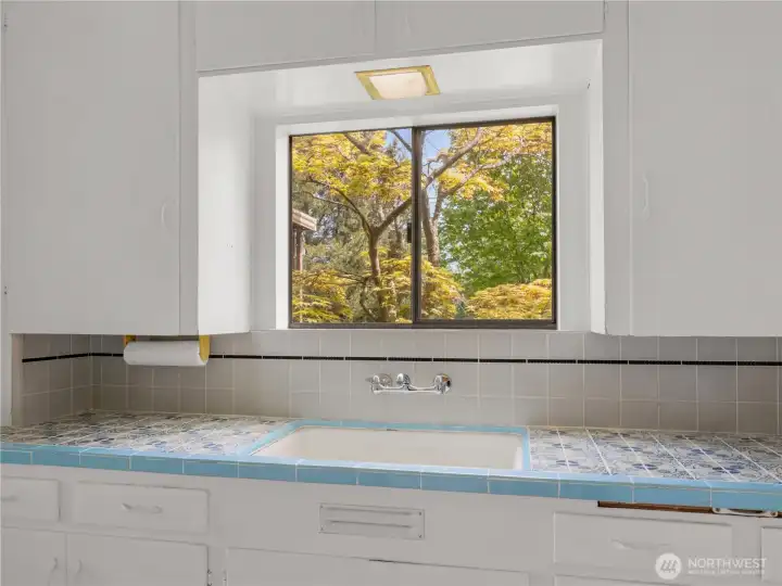 Kitchen window overlooks a beautifully landscaped garden, bringing in peaceful greenery and a serene, natural backdrop to everyday living.