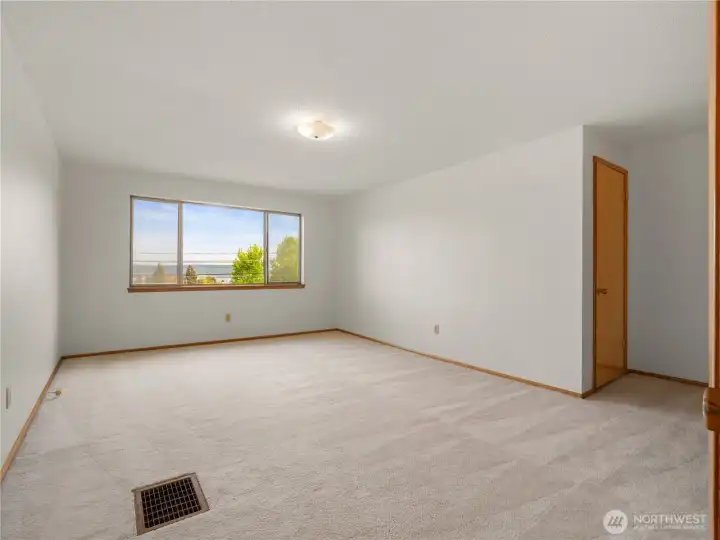 Spacious upstairs primary bedroom showcases incredible views of Puget Sound, creating a peaceful retreat filled with natural light and tranquility.