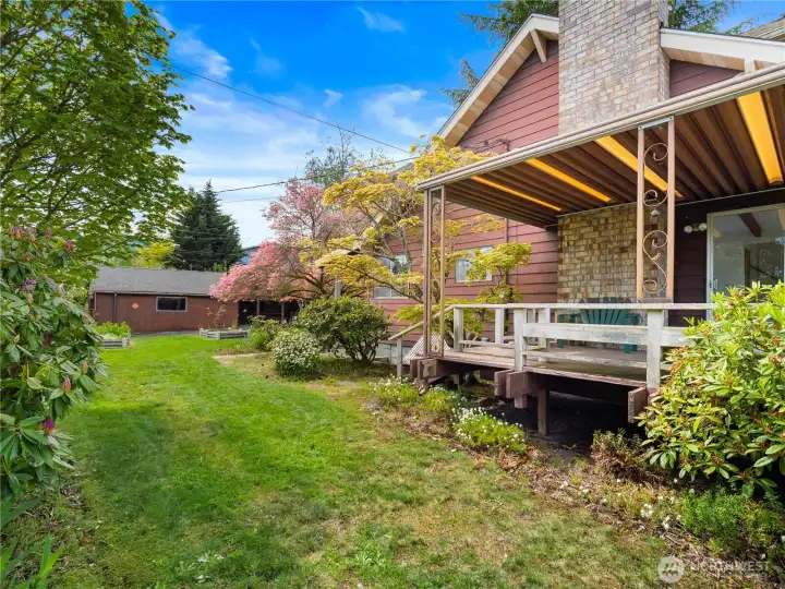 Side yard view highlights the private outdoor space off the deck, framed by mature landscaping that enhances the home’s peaceful North Tacoma setting.