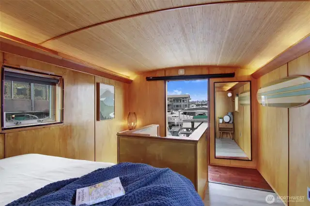 The upstairs is the main bedroom. It has views from a window in every direction.  That is a floor length mirror and to the left of the mirror is the door leading out to the decks.