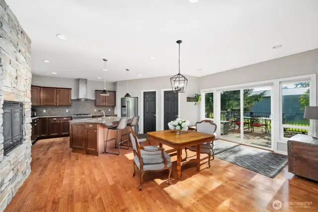 Spacious open kitchen with fireplace, dining area, island and sliding doors to back deck & yard