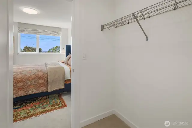 Walk-in closet flowing into primary bedroom.