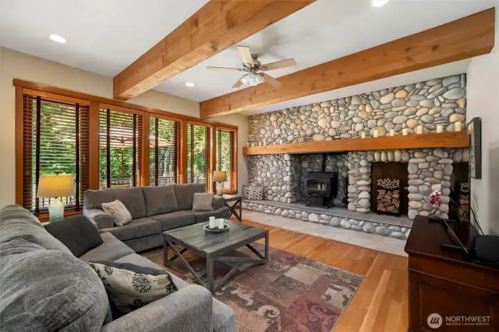 Focal point of living space is the river rock wall with wood burning stove. This keeps home warm and cozy.  Wood wrapped beams, vaulted ceilings make this such an inviting space to relax.