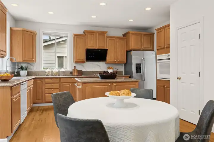 Generous breakfast nook surrounded by hardwood floors and tall light-filling windows
