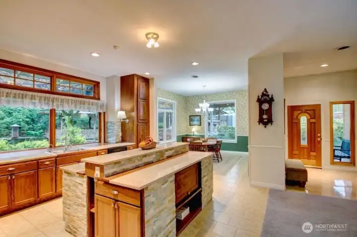 View of kitchen, kitchen island, dining room as well as entryway/front door.