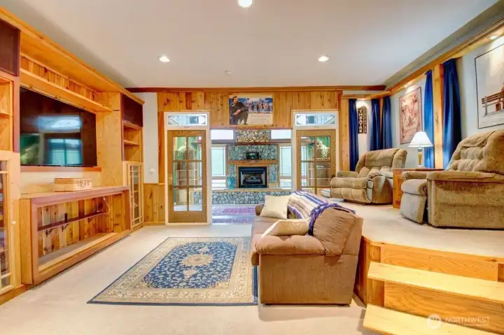 Tiered theater room with built in shelving and storage underneath top tier seating.