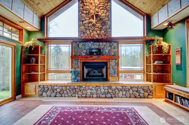 Great room overlooking the backyard. Grand stone fireplace with built in shelves and sitting bench underneath the windows.
