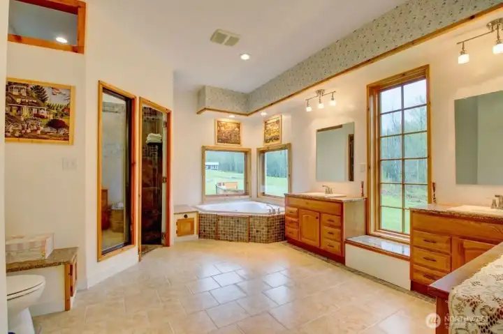 Primary en-suite bathroom with double sink, jetted tub, and walk in shower.