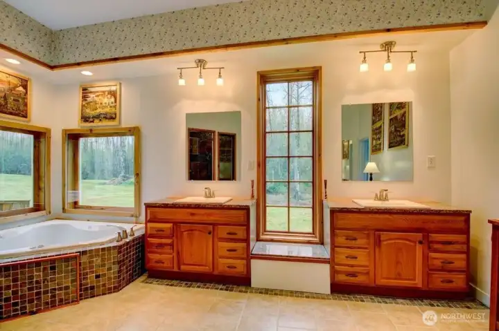View of jetted tub and double vanity sinks in the primary bathroom.