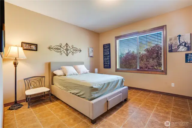 This main floor bedroom has tile floors, wood wrapped windows, views of the trees, and a walk-in closet.