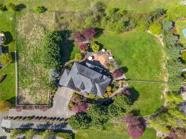 The aerial perspective highlights the vast 1.3-acre property, which features well-established landscaping, extensive hardscaping, and plenty of space for recreational activities.