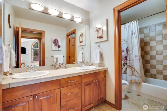 Dual sinks, tiled floors, plenty of storage and a full-sized mirror complete the upstairs bathroom. The bathtub features a tiled surround too.
