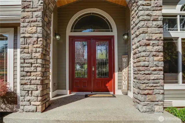 The inviting front entrance features a stone facade, doors, and harmonious curved window accents.