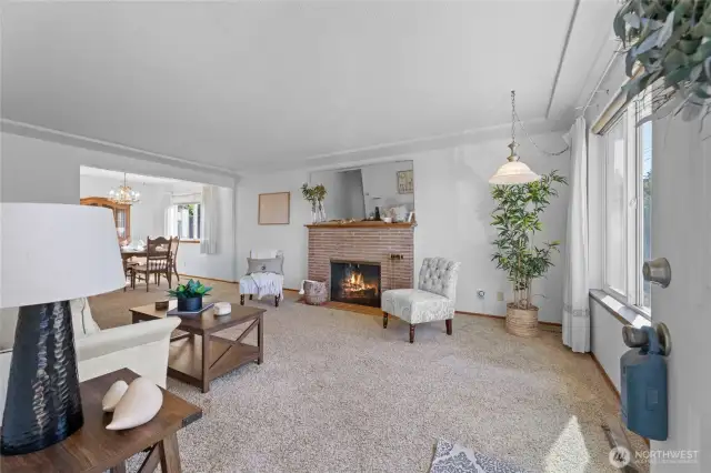 This spacious living room with a wood fireplace has original hardwood floors under the carpet