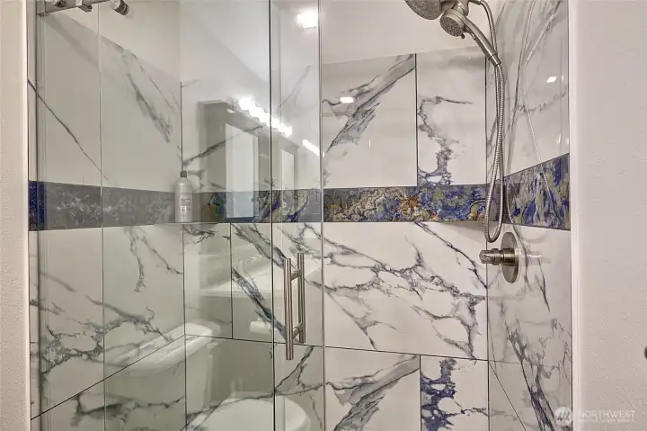 Primary bath includes a walk-in shower with a beautifully designed custom door.