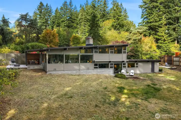 This house is cool to view from every angle!   Take note of the door to the right of the white lounge chairs.  Accessed via a short few steps along a covered overhang from the lower slider, this additional space could easily be finished off into a fantastic home office.  A window could be added on the back side for natural light.